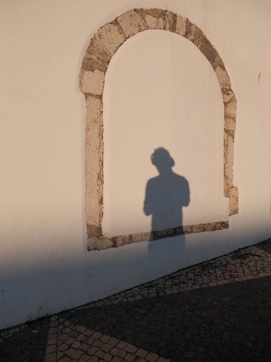 A figure's shadow cast within a stone arch.