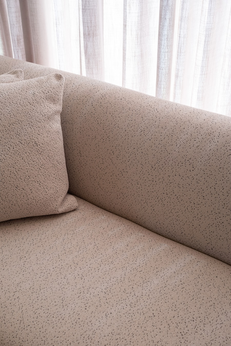 Close detail of a pale upholstered sofa arm.
